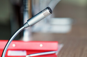 Nahaufnahme eines freigestellten Mikrofons in einem Sitzungssaal mit Block, Ordner und Stift auf...