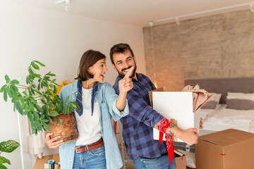 Couple carrying cardboard boxes while moving in new apartment
