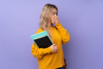 Teenager Russian student girl isolated on purple background covering mouth and looking to the side