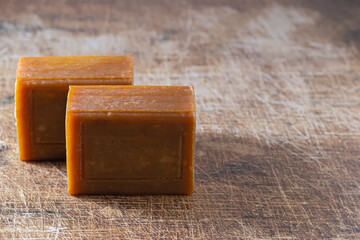 Two pieces of brown natural soap on a wooden surface. Place for your text.