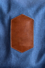 Piece of brown leather with layering over blue denim jeans.