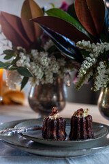 chocolate muffins in ceramic plates with fork and knife, textile napkin and flowers on wooden table