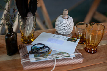 Hand crafted gift, glass bottles, deer figurines, ball of rope and scissors on rustic wooden table