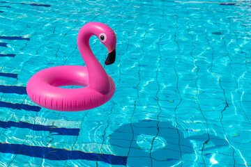 Summer time. Pink inflatable flamingo in pool water for summer beach background. Funny bird toy for kids. © Maksym
