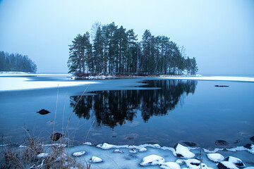 frozen blue lake with an island, snowy beach