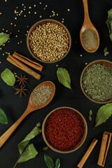 Wide variety spices and herbs on background of black table