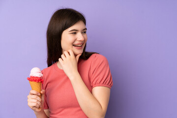 Young Ukrainian teenager girl holding a cornet ice cream over isolated purple background thinking an idea and looking side