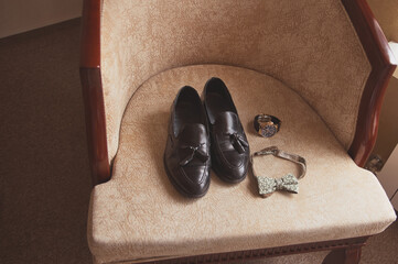 wedding mens shoes on an armchair with clock