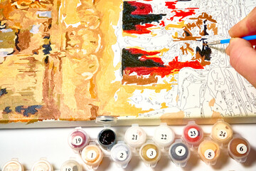 Man holding a brush and paints a picture, drawing by numbers.