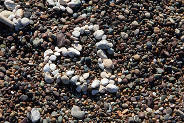 White heart made of tiny pebbles on darker pebbles at the beach. Symbolic of love and romance