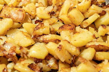 Closeup of appetizing fried potatoes with onions on a frypan. Shallow dept of field. Selective focus.