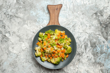 Above view of fresh and healthy vegetable salad on wooden cutting board on white background