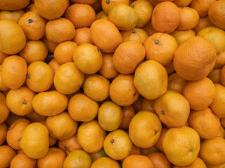 Background of a large number of orange mandarin (Citrus reticulata) fruits. Background from fruits on the showcase. Harvest orange mandarin.