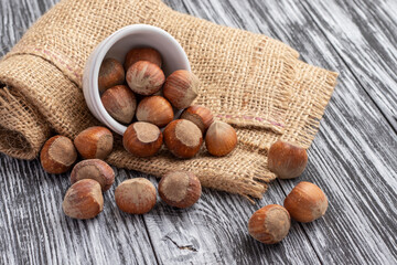 Whole hazelnuts scattered on a black wooden table.
