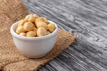 Peeled nuts in white bowl on black wooden table.