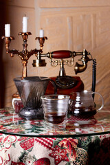 A table in a vintage cafe with a glass of alternatively prepared coffee, coffee gadgets and a vintage telephone and candlestick