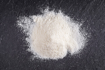 Obraz na płótnie Canvas granulated milk powder on a dark stone background