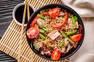 delicious glass noodles with tuna and vegetables on a dark wooden rustic background