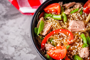 delicious glass noodles with tuna and vegetables on a dark stone background