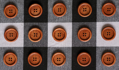 Fototapeta premium Round wooden brown sewing buttons isolated on textile background. Top view . Close up. Macro.