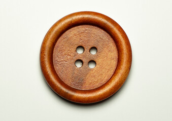 Single round wooden brown sewing button isolated on white background.  Top view . Close up. Macro.