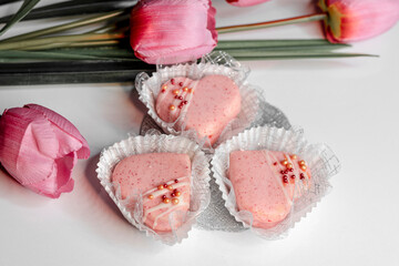 Decorated heart shaped cookies and sprinkles with a strawberry ice cream and flowers on white background . Valentine's day treat