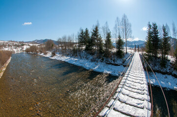 Suspension bridge in the winter mountains
