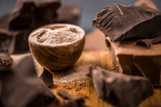 Ground Chocolate In Wooden Bowl Next To Chunk Of Chocolate