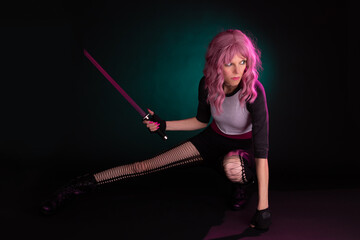 Fototapeta premium Punk rock sexy female assassin with pink hair wearing black, holding a weapon.