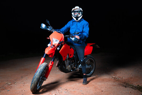 Enduro Racer Sitting On His Motorcycle  In The Night. Black Background