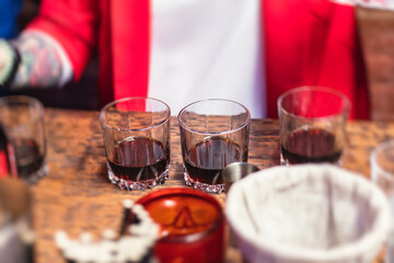 Beautiful row of different colored alcohol cocktails on a party, whiskey, scotch whisky, and others, glasses on a bar counter, bar stand, with bartender in the background