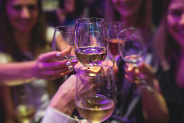 People celebrate and raise glasses, cheering with alcohol glasses with wine and champagne in the restaurant on corporate christmas birthday party event or wedding celebration