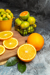 Vertical view of fresh citrus fruits on wooden cutting board on newspaper on gray background
