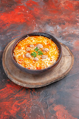 Vertical view of delicious noodle soup with chicken on wooden cutting board on dark background