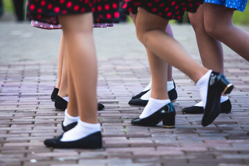 Young women wearing vintage polka dot dresses dancing in city park, close up view of same black...