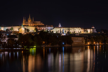 Obraz na płótnie Canvas old illuminated prague castle and charles bridge and st. vita church lights from street lights are reflected on the surface of the vltava river in the center of prague at night in the czech republic