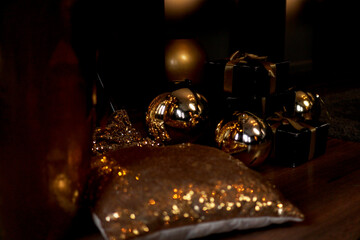 Black gift box with golden ribbon and big gold New Year balls on black background for greeting card. Winter festive composition with copy space.
