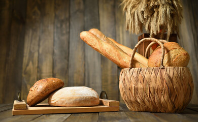 Still life with fresh various breads in a wicker basket on a wooden background