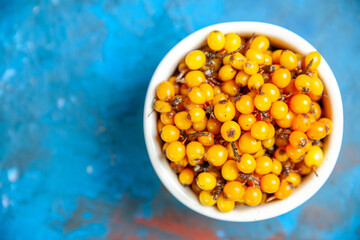 top view sea buckthorn in bowl on blue background free space
