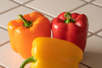 Three bell peppers waiting to be eaten. Red bell pepper, yellow bell pepper and orange bell pepper. - Powered by Adobe