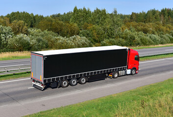 Truck with semi-trailer driving along highway on the sunset background. Goods delivery by roads. Services and Transport logistics. Soft focus.