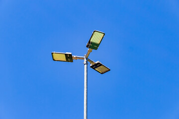 Poste de iluminação pública com céu azul ao fundo.