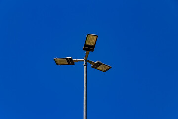 Poste de iluminação pública com céu azul ao fundo.