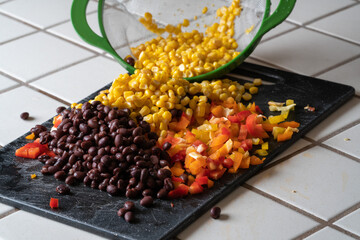 Corn, black beans and bell peppers being prepared for a meal.