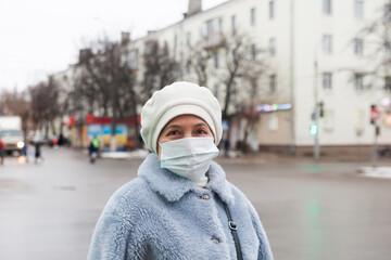 Obraz premium Old senior woman in a medical protective face mask on town street