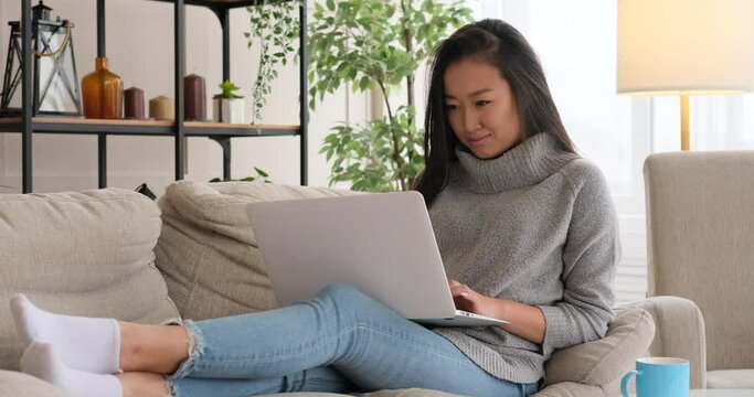Happy woman using laptop on sofa at home