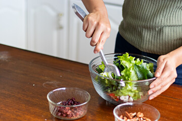 Hands of a woman mixing with a spoon, a bowl of salad