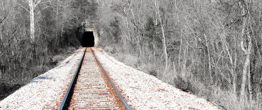 Railroad Tracks leading into a dark black tunnel of unknown. Parallel tracks perspective vanishing point.
