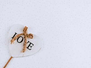 Wooden heart.

Wooden heart with the inscription love and a jute rope on the left on an abstract background with a place for text on the right, top view close-up.