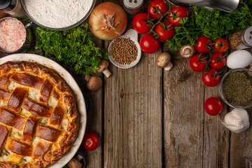 Ruddy pie with meat and mushrooms on wooden table with variety of ingredients background. Cooking process. Backstage of preparing tasty meal. View from above. Flat lay. Cookbook. Space for text.